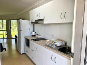 a white kitchen with a sink and a refrigerator at Bulgon Lodge in Collinsville