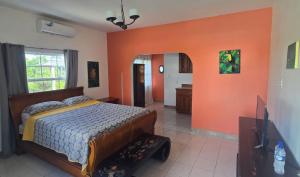 a bedroom with a bed and an orange wall at Bamboleo Inn in Ladyville +62 photos