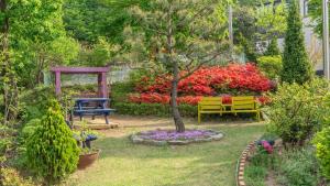 a garden with a tree and a bench and flowers at Gangwha Jeongwon Pension in Incheon