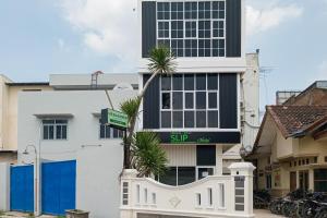 a white building with palm trees in front of it at Urbanview Hotel SLIP Pringsewu by RedDoorz in Margakaya +4 photos