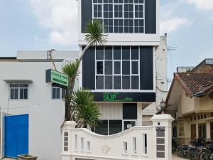 a white building with palm trees in front of it at Urbanview Hotel SLIP Pringsewu by RedDoorz in Margakaya