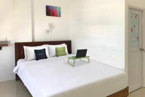 a white bed with a laptop sitting on top of it at Urbanview Hotel SLIP Pringsewu by RedDoorz in Margakaya