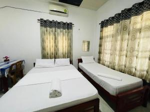 a bedroom with two beds and a window with curtains at Golden Palace Yala in Tissamaharama