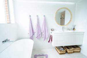 a white bathroom with a sink and a mirror at The Chelsea Beachside Apartment in The Entrance +25 photos