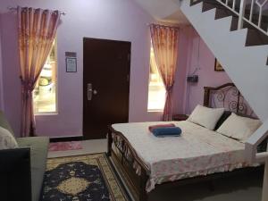 a bedroom with a bed with purple walls and a staircase at Dan's Homestay Bangau in Temerloh +6 photos