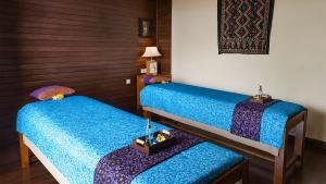 two twin beds in a room with blue sheets at Pramana Nusa Ceningan in Nusa Lembongan