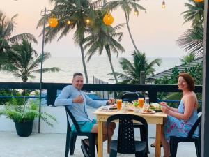 a man and woman sitting at a table eating food at Induwara Villa in Ahungalla