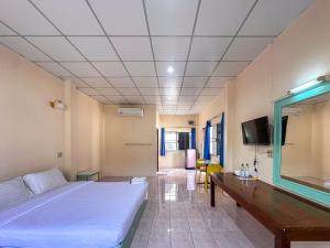 a room with a bed and a table and a tv at Chumphon Park Resort in Chumphon