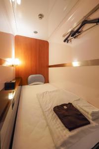 a small room with a bed with a bag on it at ファーストキャビン松江 in Matsue