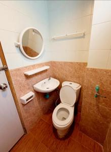 a bathroom with a toilet and a sink and a mirror at เพิ่มพูนแมนชั่น พิษณุโลก Phoempun Mansion in Sathani Phitsanulok