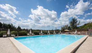 ein großer Pool mit Stühlen und Sonnenschirmen in der Unterkunft Happy Village in La Giustiniana