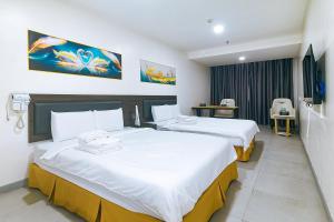 a hotel room with two beds with white sheets at Luna Hotel Pasay in Manila