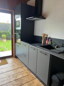 a kitchen with white cabinets and a sink and a window at Ô Chalet Normand in Colomby