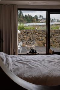 a bedroom with a bed and a large window at 바티하우스 in Ara-ri
