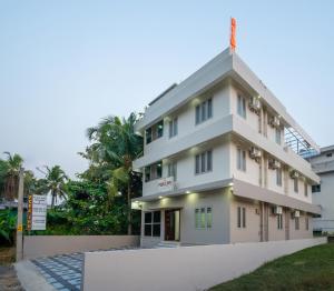 a large white building with trees in the background at FORA Inn in Cochin