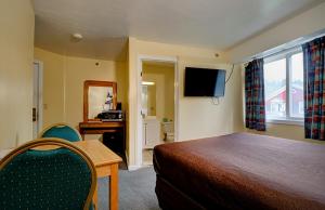 a bedroom with a bed and a desk and a television at Classic Inn in Saco