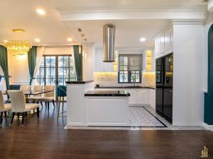 a kitchen with white cabinets and a dining room at Phan Thiết Nova World Malibu 2 Villa in Phan Thiet
