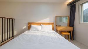 a bedroom with a white bed with a desk and a window at Gapyeong Orion PoolVilla pension in Gapyeong +16 photos