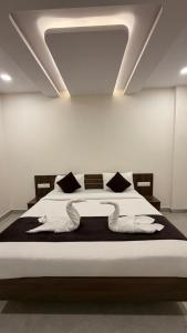 a bedroom with a bed with white sheets and pillows at SKB Suites in Mysore