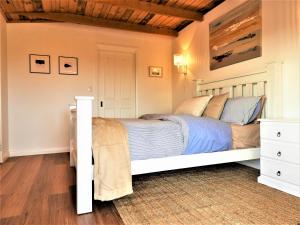 a bedroom with a white bed and a wooden ceiling at Driftwood Cottage in Dolphin Sands