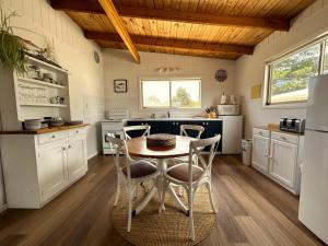 a kitchen with white cabinets and a table and chairs at Driftwood Cottage in Dolphin Sands +10 photos