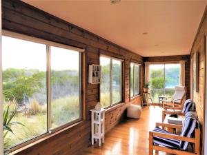 a room with wooden walls and windows in a house at Driftwood Cottage in Dolphin Sands