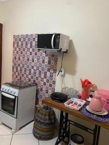 a kitchen with a stove and a microwave and a table at Divino Lugar in Olímpia