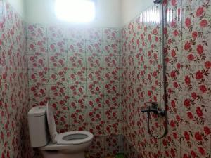 a bathroom with a toilet and flowers on the wall at Bromo Seruni Astungkara Homestay in Probolinggo