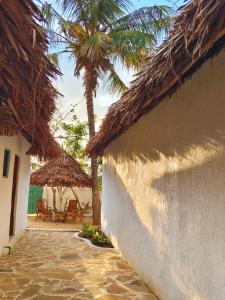a resort with a palm tree and chairs and a building at Sawa Sawa Beach Hotel&Backpacks in Malindi