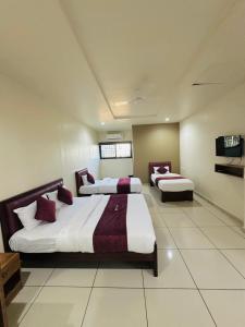 a bedroom with two beds and a flat screen tv at Atland Residency in Calicut