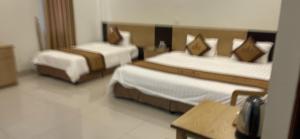 a hotel room with two beds and a table at AVS Nội Bài Hotel in Sóc Sơn