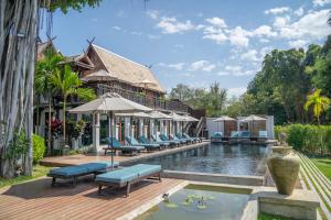 a pool at a resort with blue chairs and a house at Buri Sriping Riverside Resort & Spa in Chiang Mai