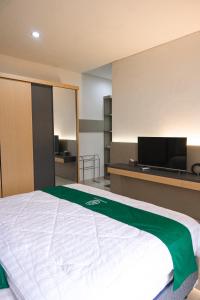 a bedroom with a bed and a flat screen tv at Sampai Villa Vasana in Yogyakarta