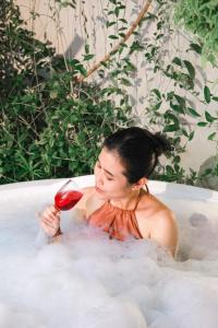 a woman sitting in a bathtub with a glass of wine at Sampai Villa Vasana in Yogyakarta