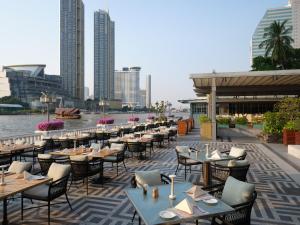 a restaurant with tables and chairs next to a river at Mandarin Oriental, Bangkok in Bangkok