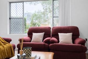 a red couch in a living room with a window at Epping Station Apartments in Epping