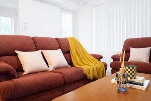 a living room with a brown couch with a yellow blanket at Epping Station Apartments in Epping