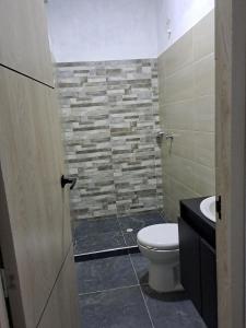 a bathroom with a toilet and a stone wall at Finca Villeta in Villeta +7 photos