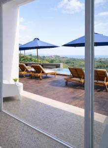 a view of a patio with chairs and umbrellas at ELEVATE - Uluwatu, Bali in Uluwatu