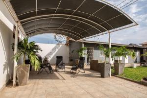 a patio with chairs and a black canopy with palm trees at The View Apartments Salagi in Brusubi
