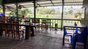 a restaurant with tables and chairs and a view of a field at Dee-maak Hostel in Thong Sala