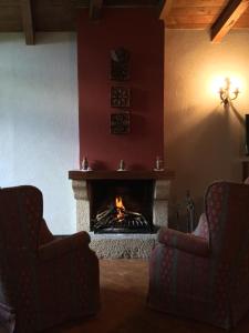 a living room with two chairs and a fireplace at Mas Pardas in Santa Pau