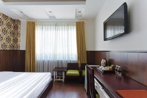 a hotel room with a bed and a desk and a television at Happy Light Central Nha Trang in Nha Trang