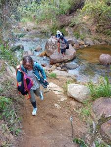 a woman and two children walking across a stream at Sinharaja-Forest Cave Camp in Ullinduwawa