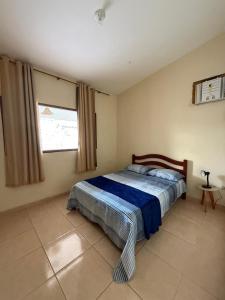 a bedroom with a bed with a blue blanket and a window at Casa Refúgio Tamandaré in Tamandaré