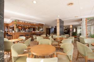 un restaurante con mesas y sillas y un bar en Hotel Sultán, en Can Picafort