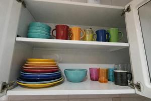 a cabinet filled with colorful plates and bowls at Casa Refúgio Tamandaré in Tamandaré +17 photos
