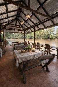a dining area with a table and benches and a river at The Scarecrow House in Ban Doem Bang (1)
