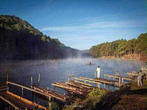 a man standing on a dock on a lake at โบว์ โฮมสเตย์ปางอุ๋ง in Ban Huai Makhuea Som