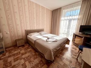 a hotel room with a bed and a television at Гостиница Караганда in Karagandy +44 photos